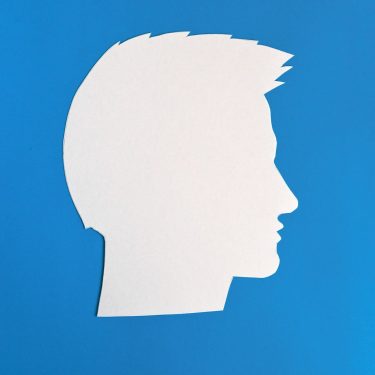 The silhouette of the guy’s head. a concept with copy space. cut out of paper on a blue background. The silhouette of the guy's head. a concept with copy space. cut out of paper on a blue background.